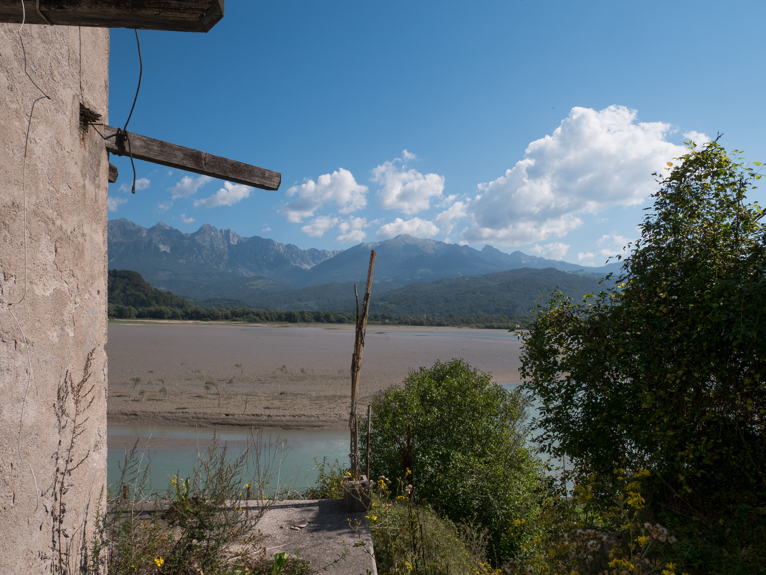 Blick aus einer Ruine über den fast leeren Stausee zu den Dolomiten